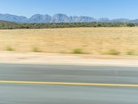 the woman is riding her motorcycle on the street near the desert mountain range of mountains