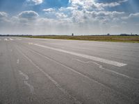 a person riding a motorcycle on an airport runway under a blue sky with white clouds