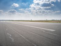 a person riding a motorcycle on an airport runway under a blue sky with white clouds