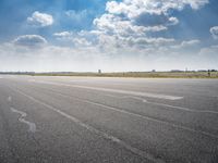 a person riding a motorcycle on an airport runway under a blue sky with white clouds