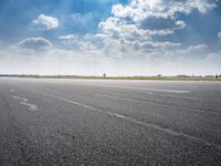 a person riding a motorcycle on an airport runway under a blue sky with white clouds