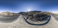 a man riding a motorcycle on top of a dirt road next to a mountain side