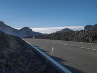 a motorcycle on a roadway passing by mountains on a sunny day on a mountain road