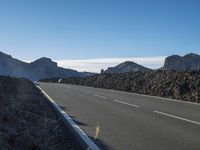 a motorcycle on a roadway passing by mountains on a sunny day on a mountain road