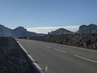 a motorcycle on a roadway passing by mountains on a sunny day on a mountain road