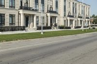 a man rides a motorcycle down a road with two apartment buildings behind him on either side