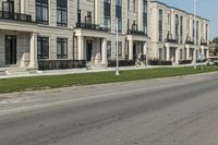 a man rides a motorcycle down a road with two apartment buildings behind him on either side