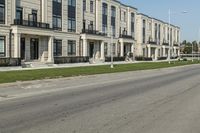 a man rides a motorcycle down a road with two apartment buildings behind him on either side