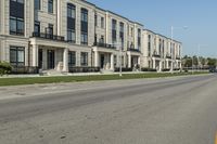 a man rides a motorcycle down a road with two apartment buildings behind him on either side