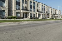 a man rides a motorcycle down a road with two apartment buildings behind him on either side