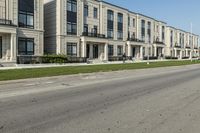 a man rides a motorcycle down a road with two apartment buildings behind him on either side