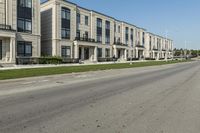 a man rides a motorcycle down a road with two apartment buildings behind him on either side