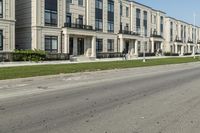 a man rides a motorcycle down a road with two apartment buildings behind him on either side