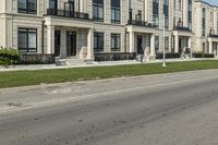 a man rides a motorcycle down a road with two apartment buildings behind him on either side