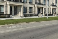 a man rides a motorcycle down a road with two apartment buildings behind him on either side