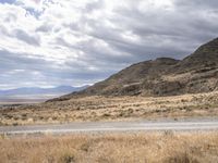 a person riding a motorcycle on the side of a road with a sky and mountains in the background