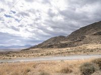 a person riding a motorcycle on the side of a road with a sky and mountains in the background