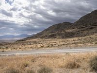 a person riding a motorcycle on the side of a road with a sky and mountains in the background