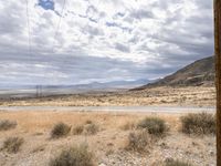 a person riding a motorcycle on the side of a road with a sky and mountains in the background