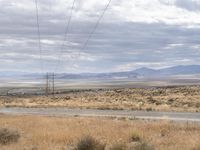 a person riding a motorcycle on the side of a road with a sky and mountains in the background