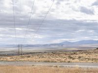 a person riding a motorcycle on the side of a road with a sky and mountains in the background