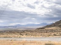 a person riding a motorcycle on the side of a road with a sky and mountains in the background