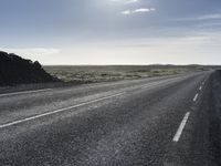 a motorcycle rider riding down a paved road near the water in the desert area in the background