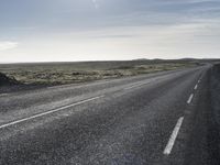 a motorcycle rider riding down a paved road near the water in the desert area in the background