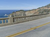 motorcycle rider on highway over cliffs near beach and ocean shore line with ocean in background