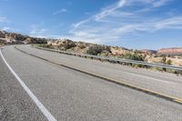 a motorcycle rider is riding on the highway in the middle of the desert with a sky background