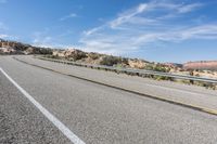 a motorcycle rider is riding on the highway in the middle of the desert with a sky background