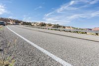 a motorcycle rider is riding on the highway in the middle of the desert with a sky background