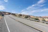 a motorcycle rider is riding on the highway in the middle of the desert with a sky background