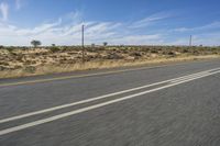 a motorcycle rider riding on an empty road in front of a mountain range with some grass and bushes