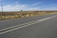 a motorcycle rider riding on an empty road in front of a mountain range with some grass and bushes