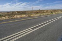 a motorcycle rider riding on an empty road in front of a mountain range with some grass and bushes