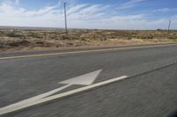 a motorcycle rider riding on an empty road in front of a mountain range with some grass and bushes