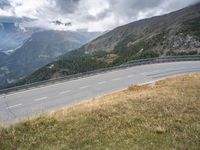 the motorcycle rider is riding down a winding road with a view of mountains in the distance