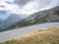 the motorcycle rider is riding down a winding road with a view of mountains in the distance