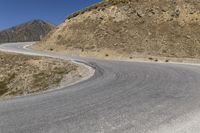 a motorcycle rider rides through a bend on the highway near the mountains in the background