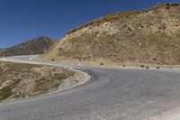 a motorcycle rider rides through a bend on the highway near the mountains in the background