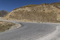 a motorcycle rider rides through a bend on the highway near the mountains in the background