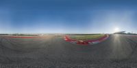 a photo of a man riding a motorcycle on a racetrack with sun shining through the sky