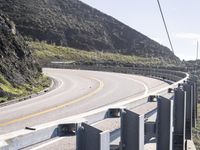 a man on a motorcycle rides down a winding road with a bird in the distance