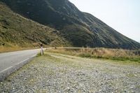 a motorcycle parked on a small mountain side road near mountains with no cars driving on it