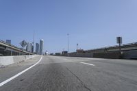 a person riding a motorcycle along a road next to a bridge with buildings behind them