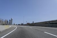 a person riding a motorcycle along a road next to a bridge with buildings behind them