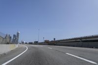 a person riding a motorcycle along a road next to a bridge with buildings behind them