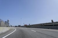 a person riding a motorcycle along a road next to a bridge with buildings behind them