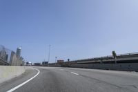 a person riding a motorcycle along a road next to a bridge with buildings behind them